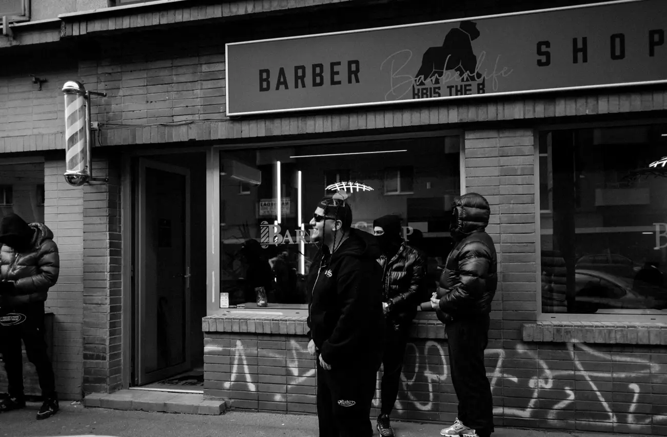 Fasáda barbershopu s barber pole a partiou pred vchodom